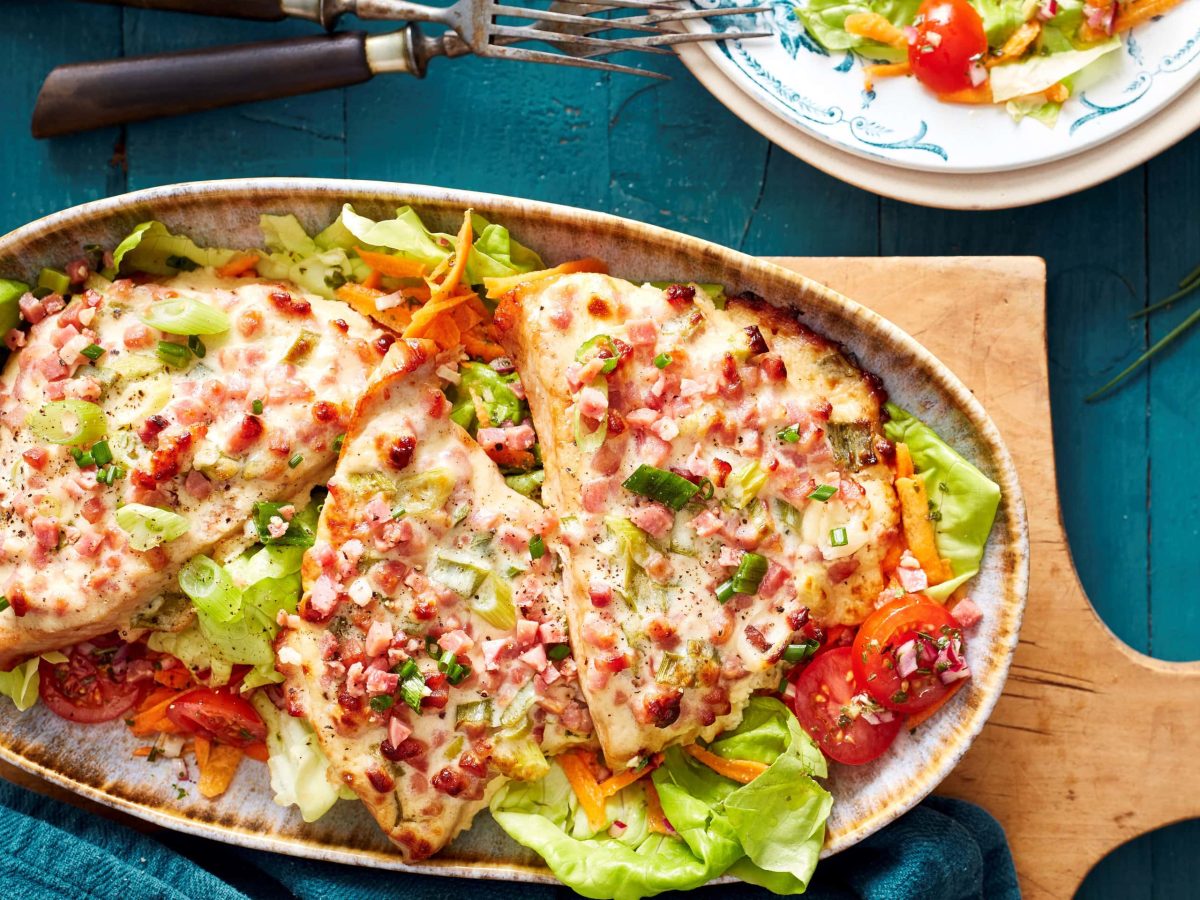 Flammkuchen-Schnitzel auf Salatbett in der Draufsicht.