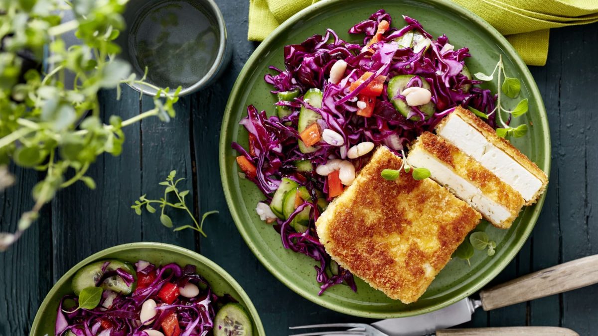 Feta-Schnitzel mit Wintersalat auf einem grünen Teller in der Draufsicht.