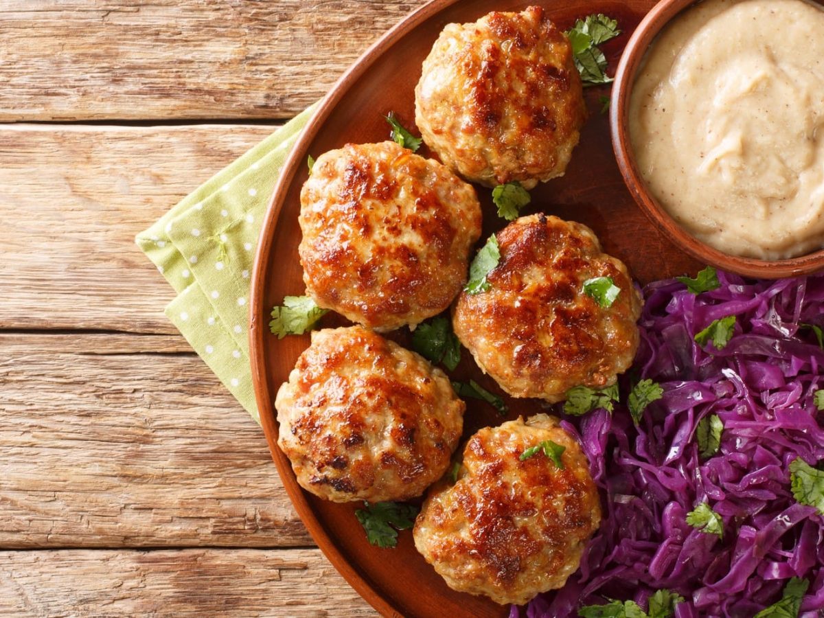 Frikadeller auf Terracotta-Teller mit Dip und Rotkohlsalat