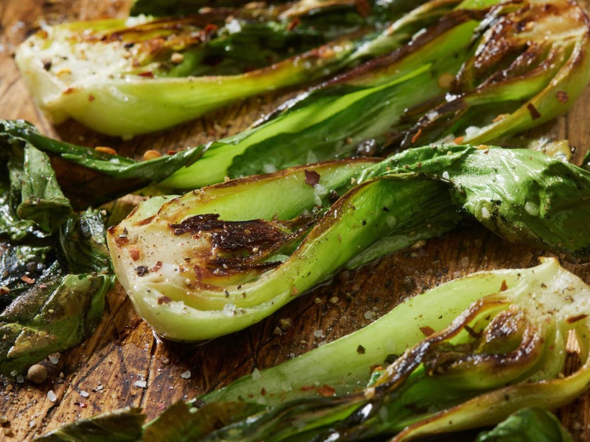 Gerösteter Pak Choi Hot & Spicy auf Holzbrett angerichtet. Draufsicht.