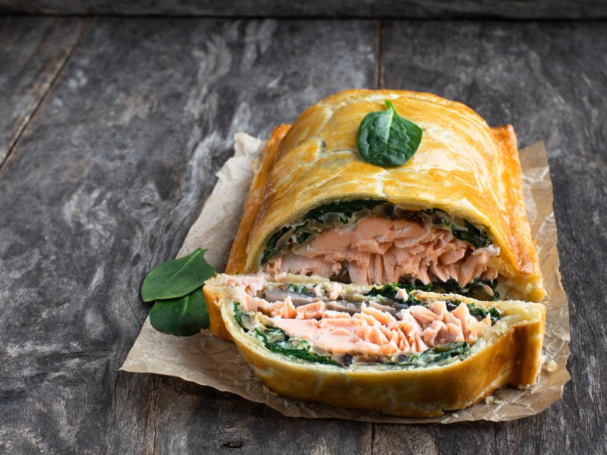 Lachs-Coulibiac Lachs Wellington auf Alufolie auf grauem Untergrund. Frontalansicht