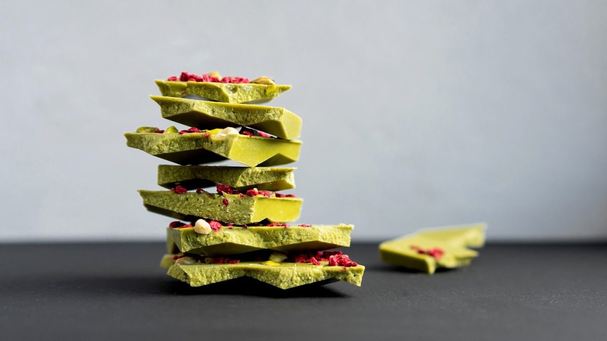 Ein paar Stücke zerbrochene Matcha-Schokolade auf einem dunklen Tisch.