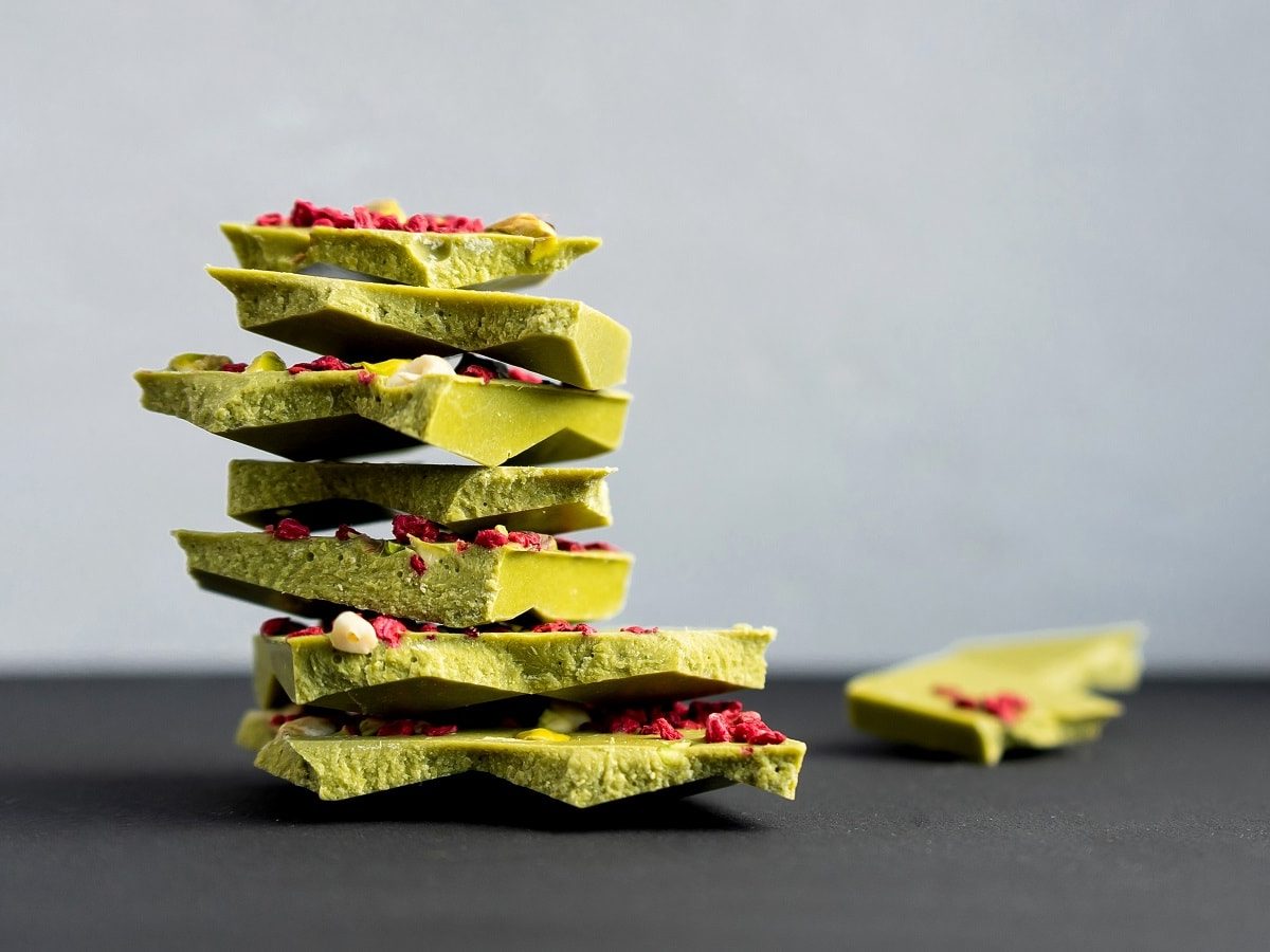 Ein paar Stücke zerbrochene Matcha-Schokolade auf einem dunklen Tisch.