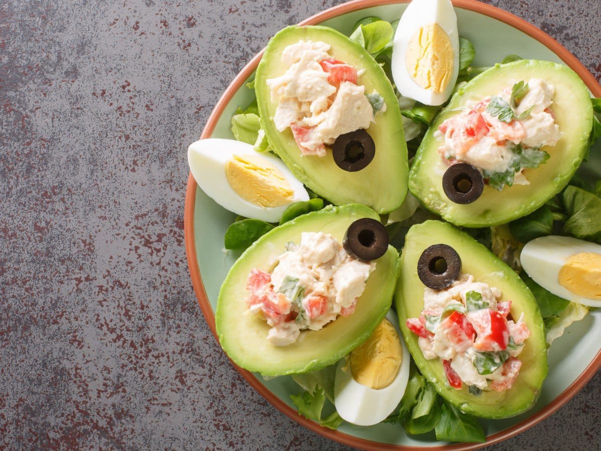 Palta Reine chilenische gefüllte Avocado mit Hähnchensalat auf Teller und grauem Untergrund. Draufsicht.