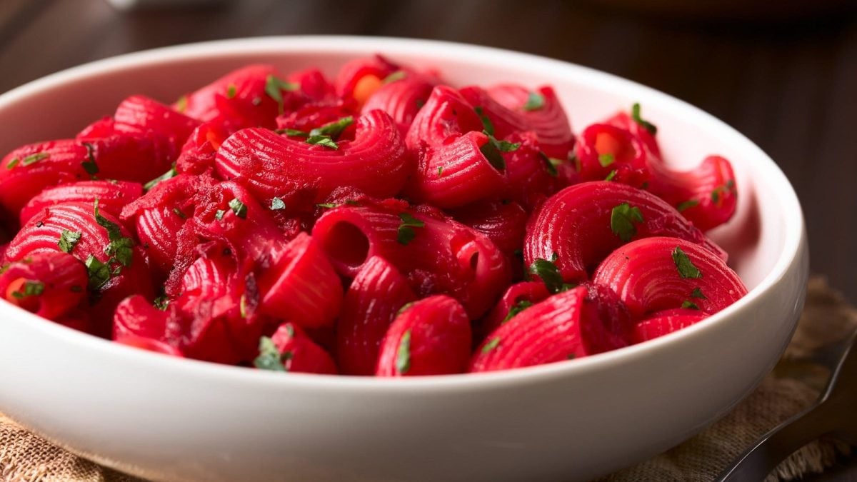 Ein tiefer Teller Pasta mit Rote-Bete-Sauce und gehacktem Basilikum.