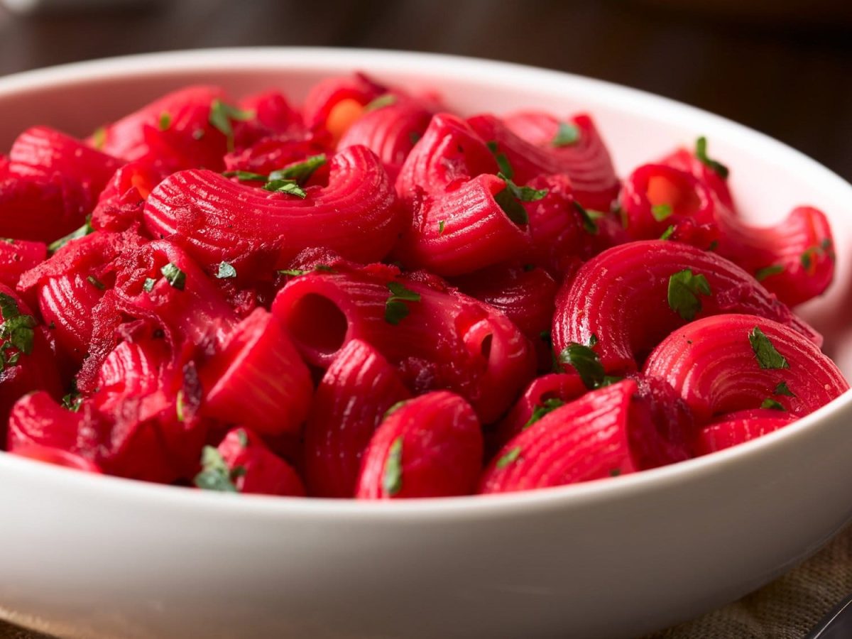 Ein tiefer Teller Pasta mit Rote-Bete-Sauce und gehacktem Basilikum.