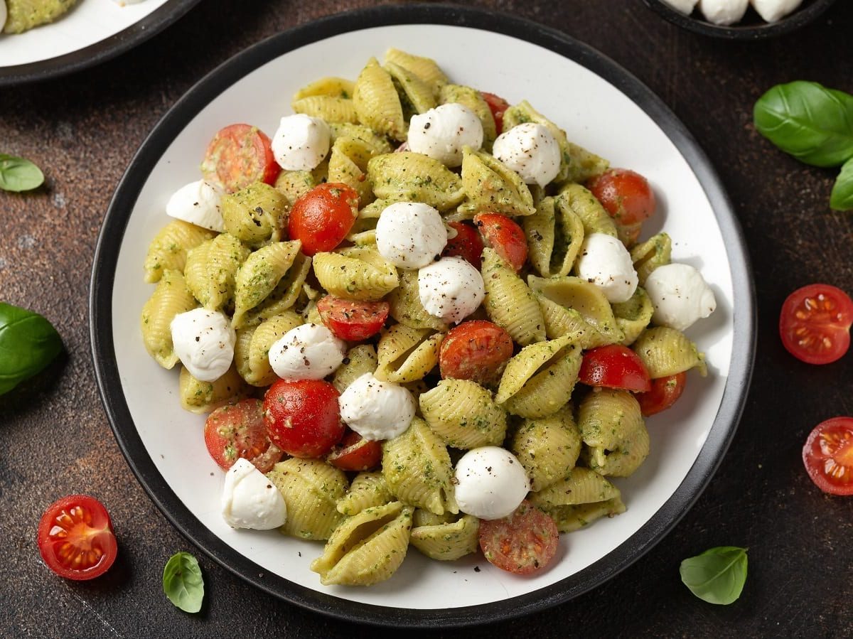 Ein Teller mit Pesto-Nudelsalat auf einem braunen Tisch.