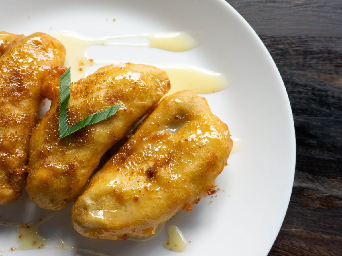 Pisang Goreng frittierte Bananen mit Honigsauce aus Indonesien auf weißem Teller. Draufsicht.