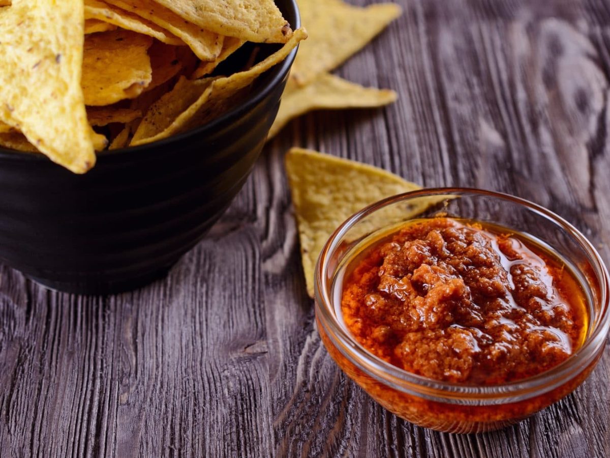 Salsa Lizano mit Nachos auf Holztisch. Draufsicht.