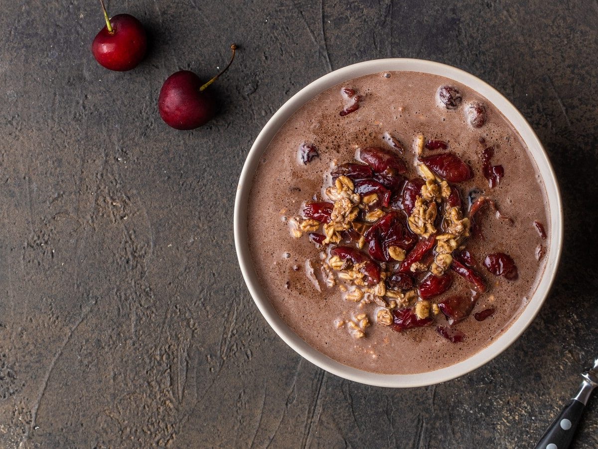 Eine runde Schüssel mit Schwarzwälder Kirschporridge auf einem grauen Steinuntergrund.