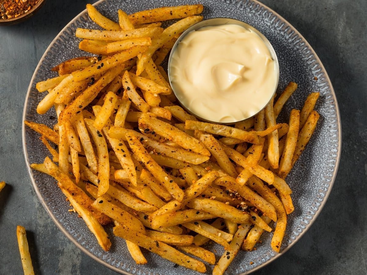 Ein grauer Teller mit Shichimi Togarashi Fries auf einem grauen Tisch.