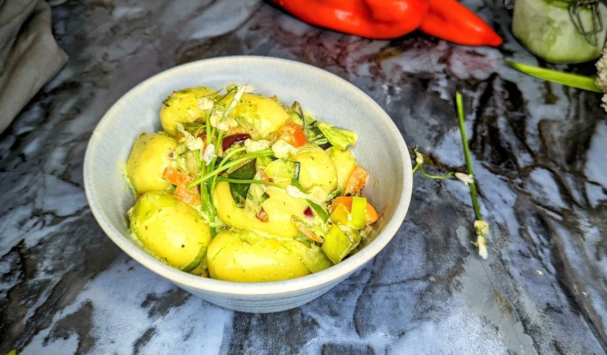 Eine schale mit den Gnocchi auf einem Marmortisch. Im Hintergrund Paprika und Pesto.