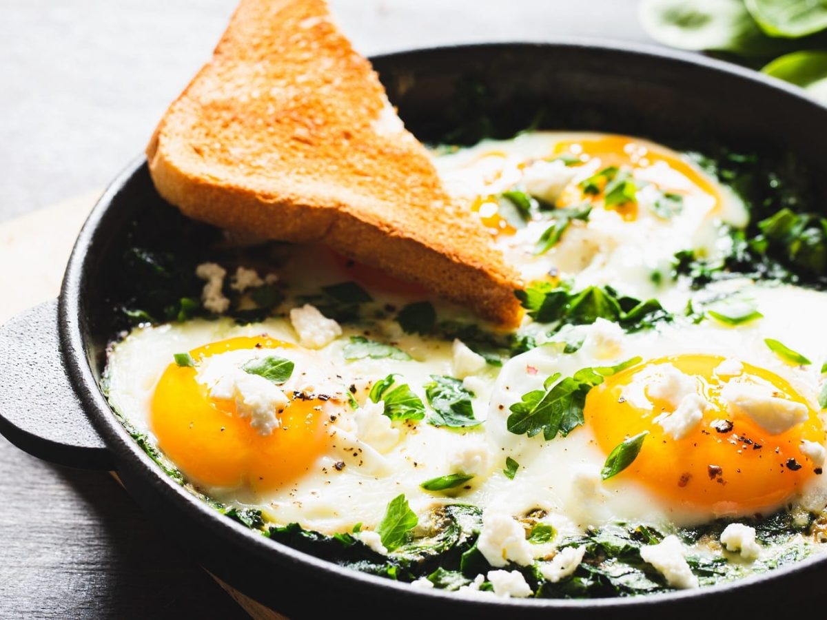 Eine Pfanne auf einem kleinen Schneidebrett mit dem Bärlauch Shakshuka.