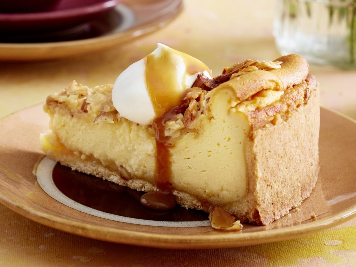 EinTeller mit einem Stück Bienenstich-Käsekuchen auf einem gelben Tisch.