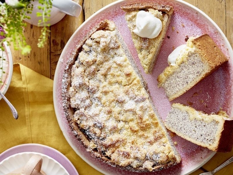 Der Mohn-Käsekuchen mit Streuseln auf einem hellen rosa Teller.