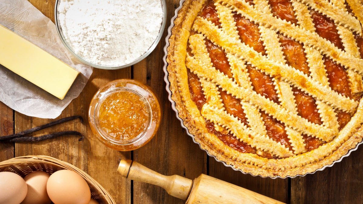 Crostata arancia auf Holztisch mit Zutaten arrangiert. Draufsicht.