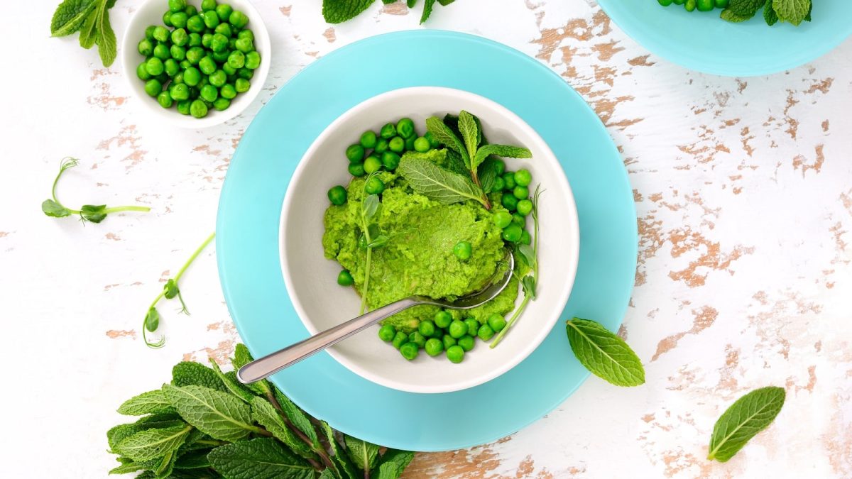 Eine Schüssel mit Erbsen-Pesto auf einem hellen Tisch.