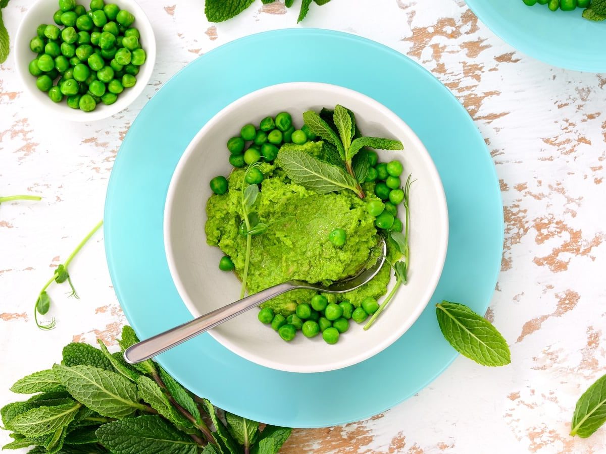 Eine Schüssel mit Erbsen-Pesto auf einem hellen Tisch.