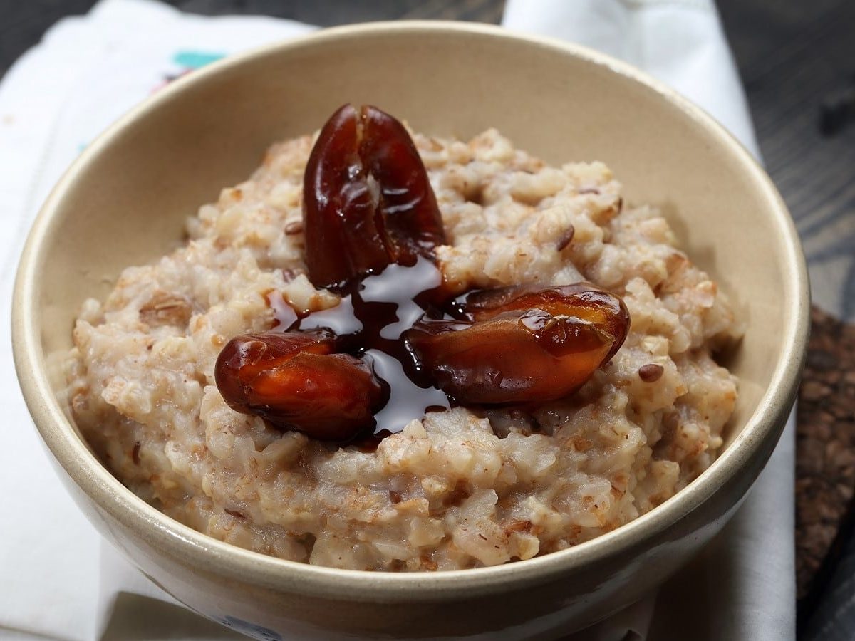 Eine Schüssel mit Tahini-Dattel-Porridge auf einem weißen Tuch.