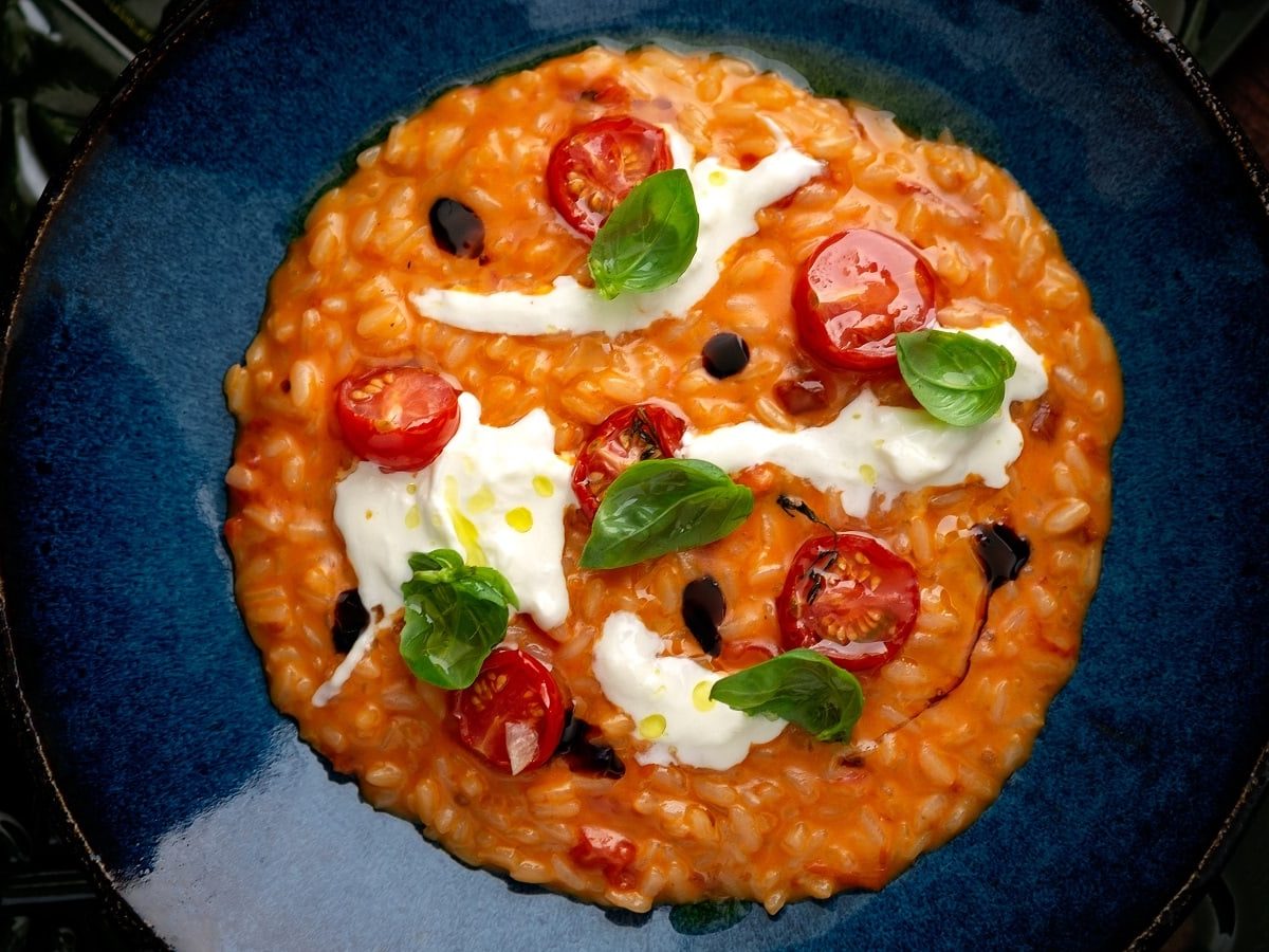 Ein blauer tiefer Teller mit Tomatencreme-Risotto.