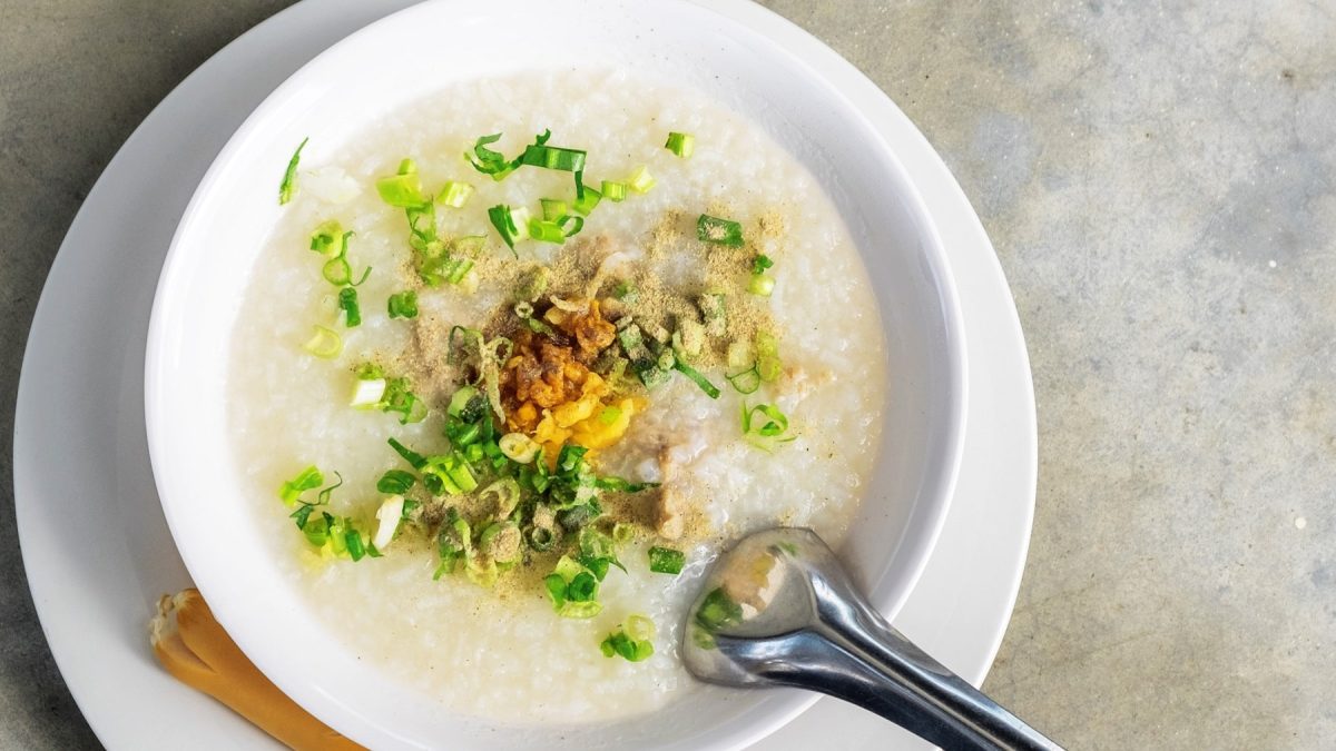 Eine weiße Schale mit der Suppe auf einem Betontisch.