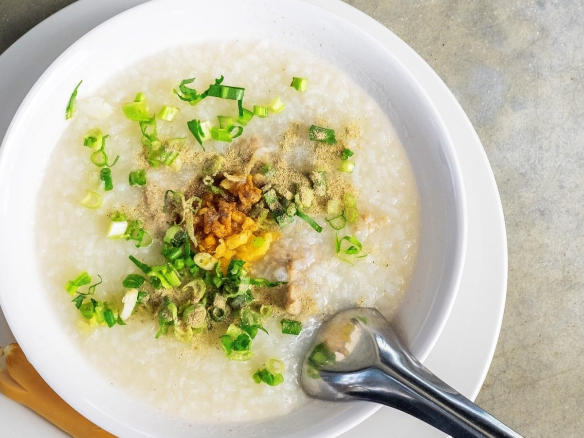 Eine weiße Schale mit der Suppe auf einem Betontisch.