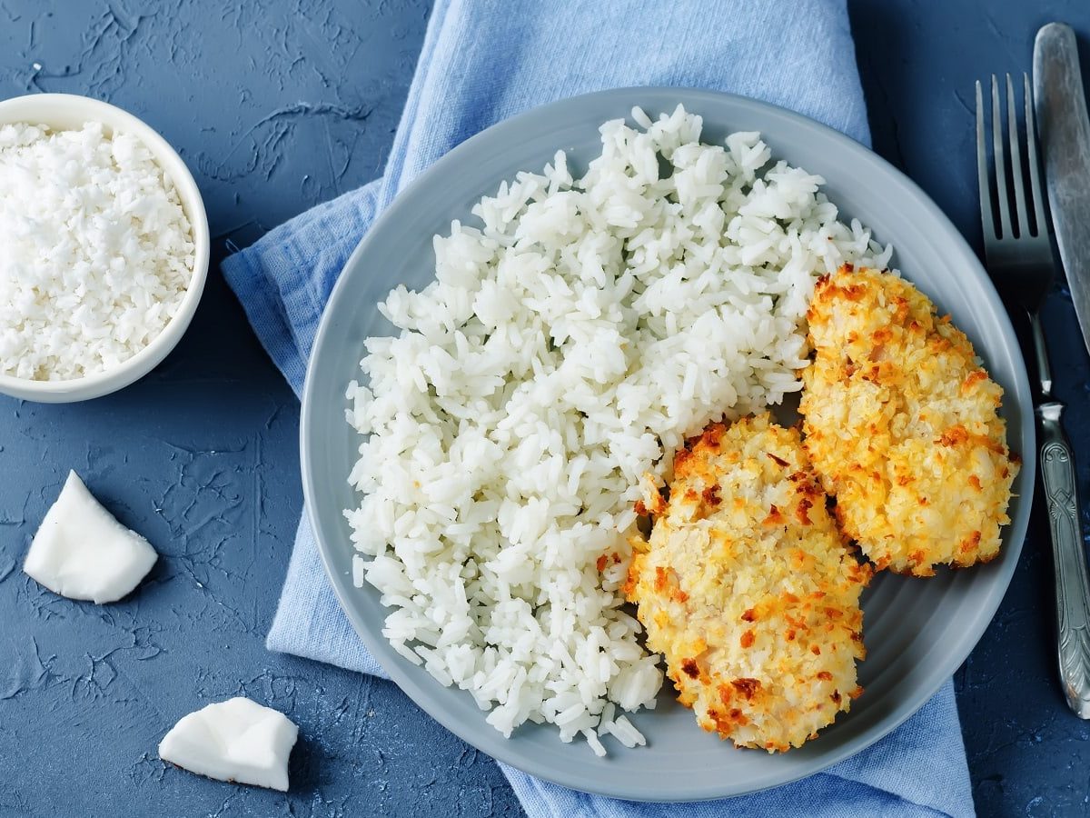 Ein blauer runder Teller mit Hähnchen mit Kokoskruste.