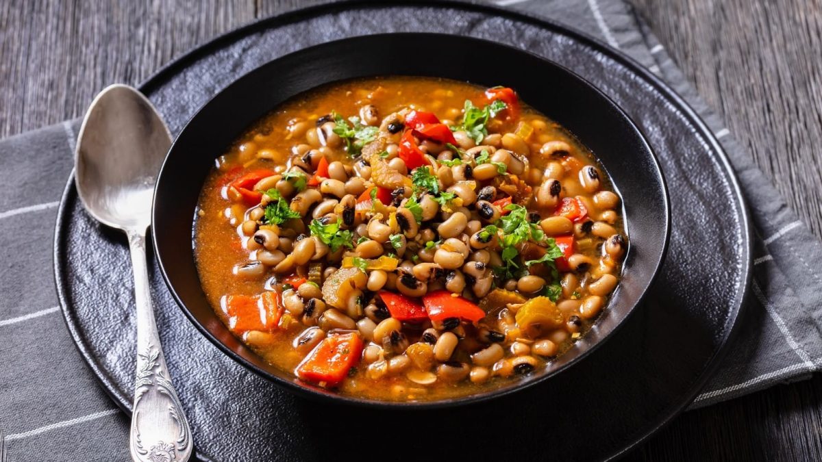 Eine schwarze Schüssel mit Hoppin John auf einem dunkelblauen Geschirrtuch.