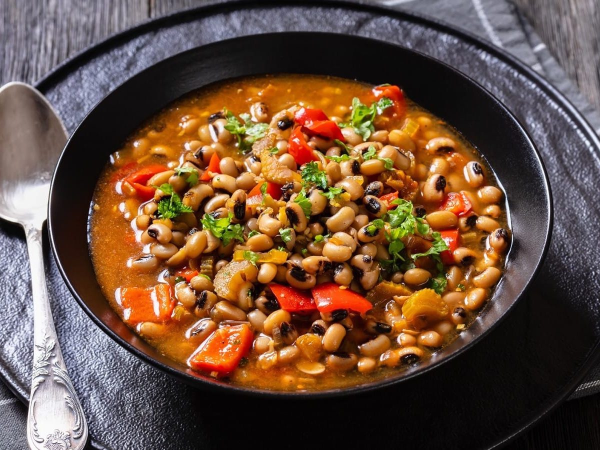 Eine schwarze Schüssel mit Hoppin John auf einem dunkelblauen Geschirrtuch.