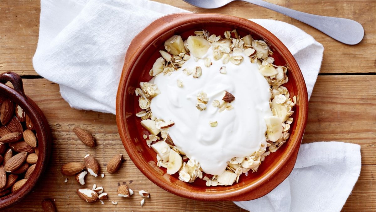 Draufsicht: Joghurt mit Knusper-Topping in einer Schüssel. Daneben die beiden werden sich nicht benehmen.