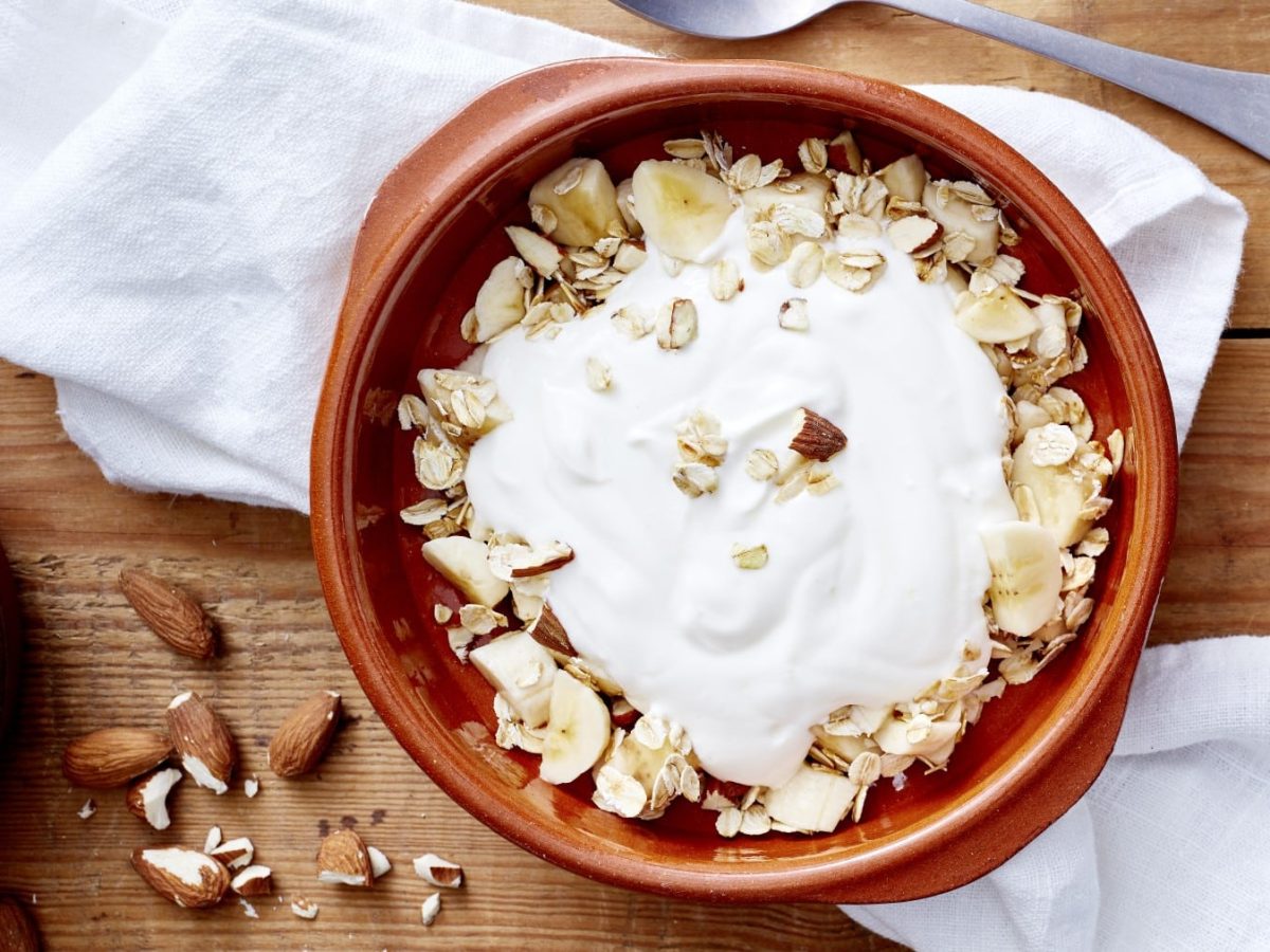 Draufsicht: Joghurt mit Knusper-Topping in einer Schüssel. Daneben die beiden werden sich nicht benehmen.