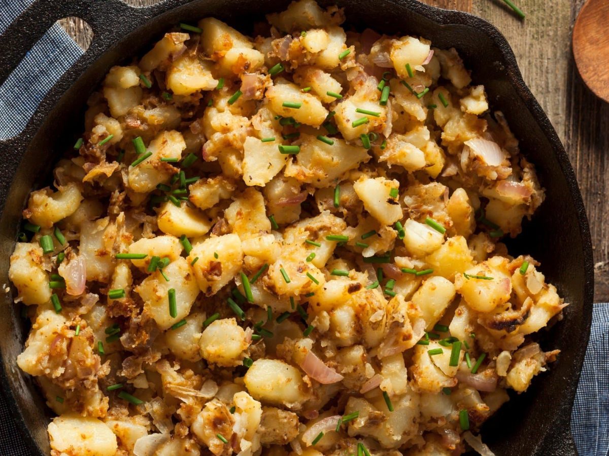 Kartoffelsterz mit Zwiebeln und Schnittlauch in gusseiserner Pfanne.