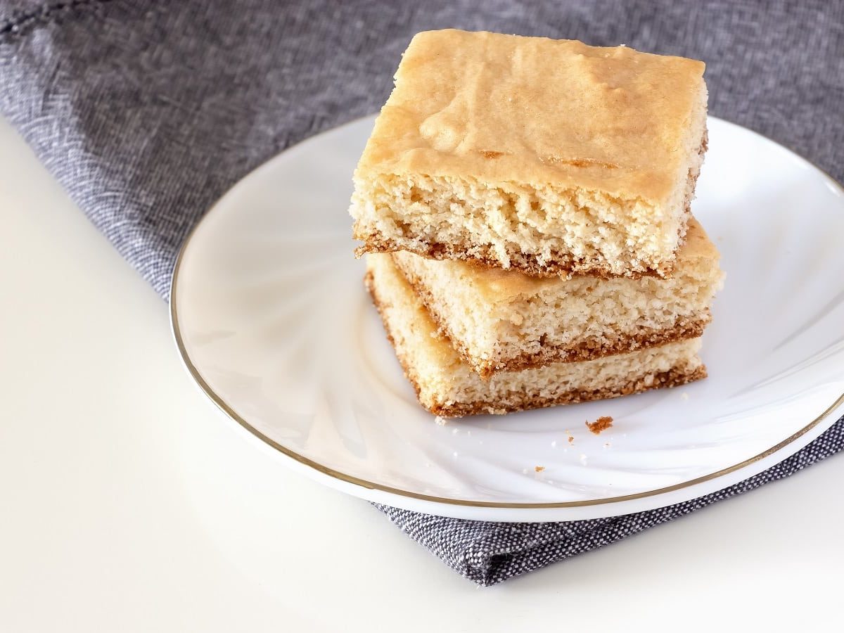 Ein weißer Teller mit einem Stapel Kokos-Blondies darauf.