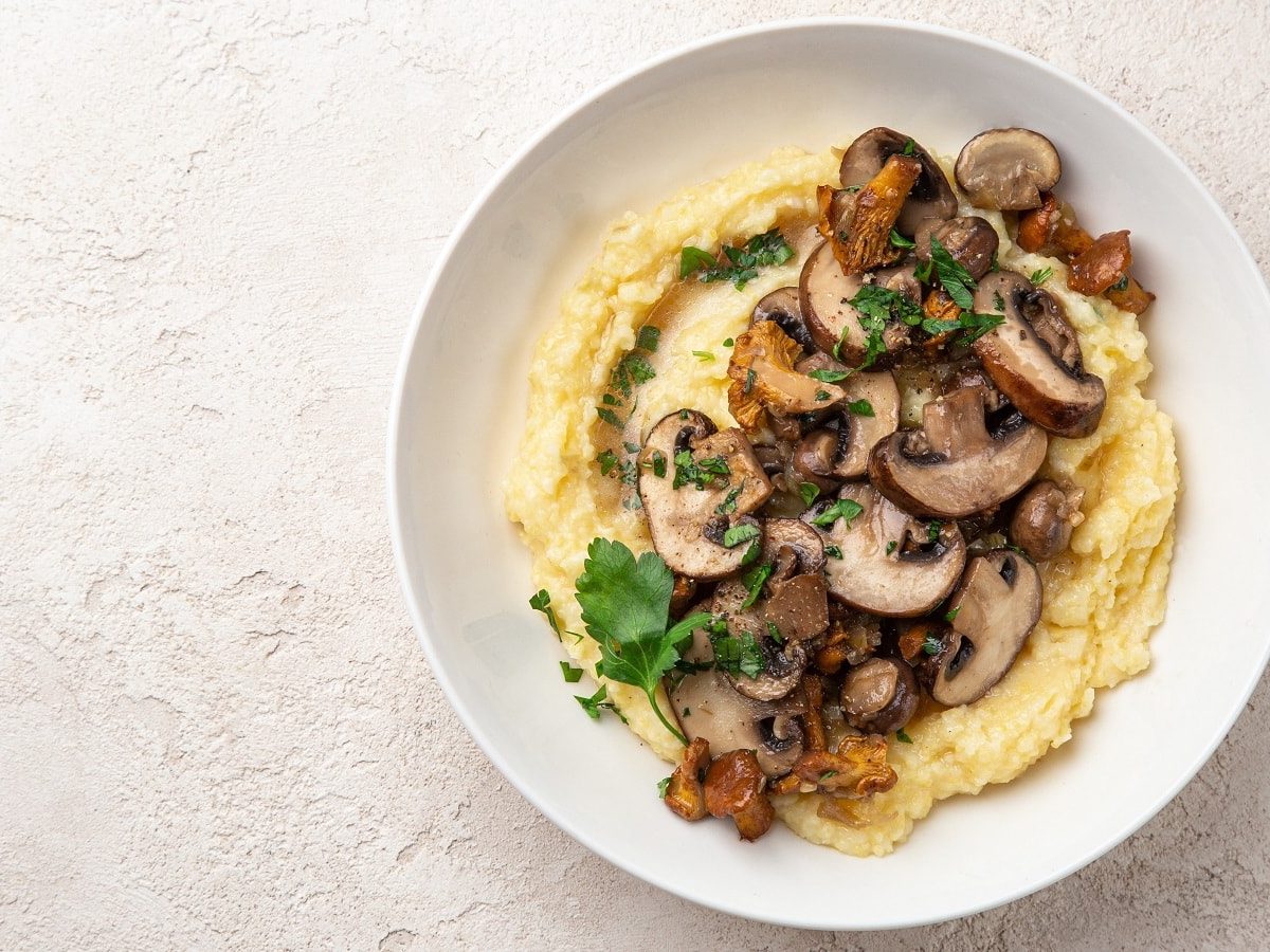 Ein weißer Teller mit Miso Polenta auf einem hellen Tisch.