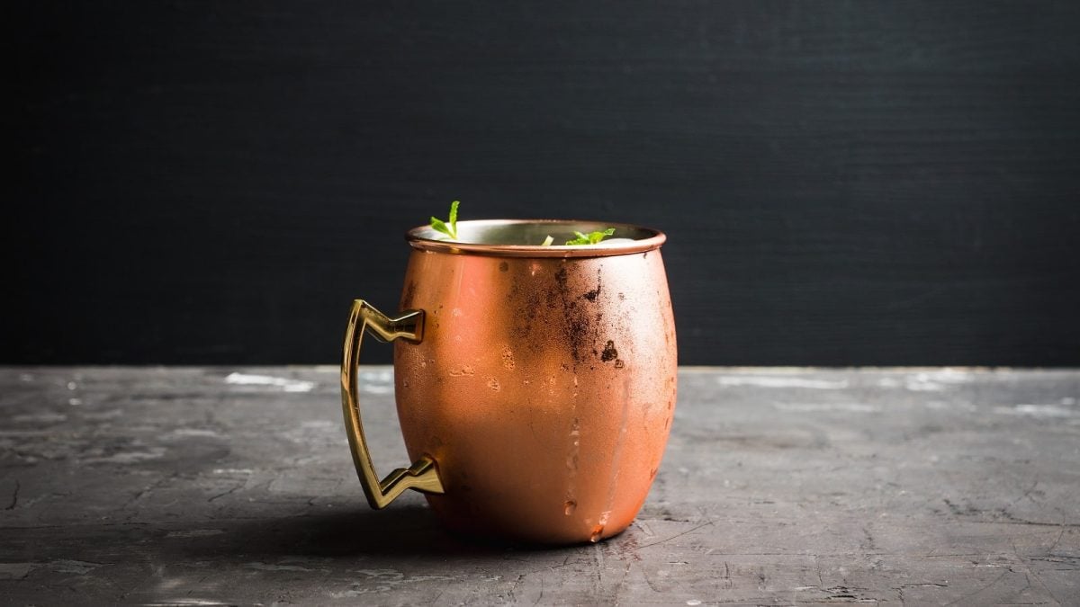 Eine kupferne Tasse mit Rhabarber Moscow Mule auf einem grauen Tisch.