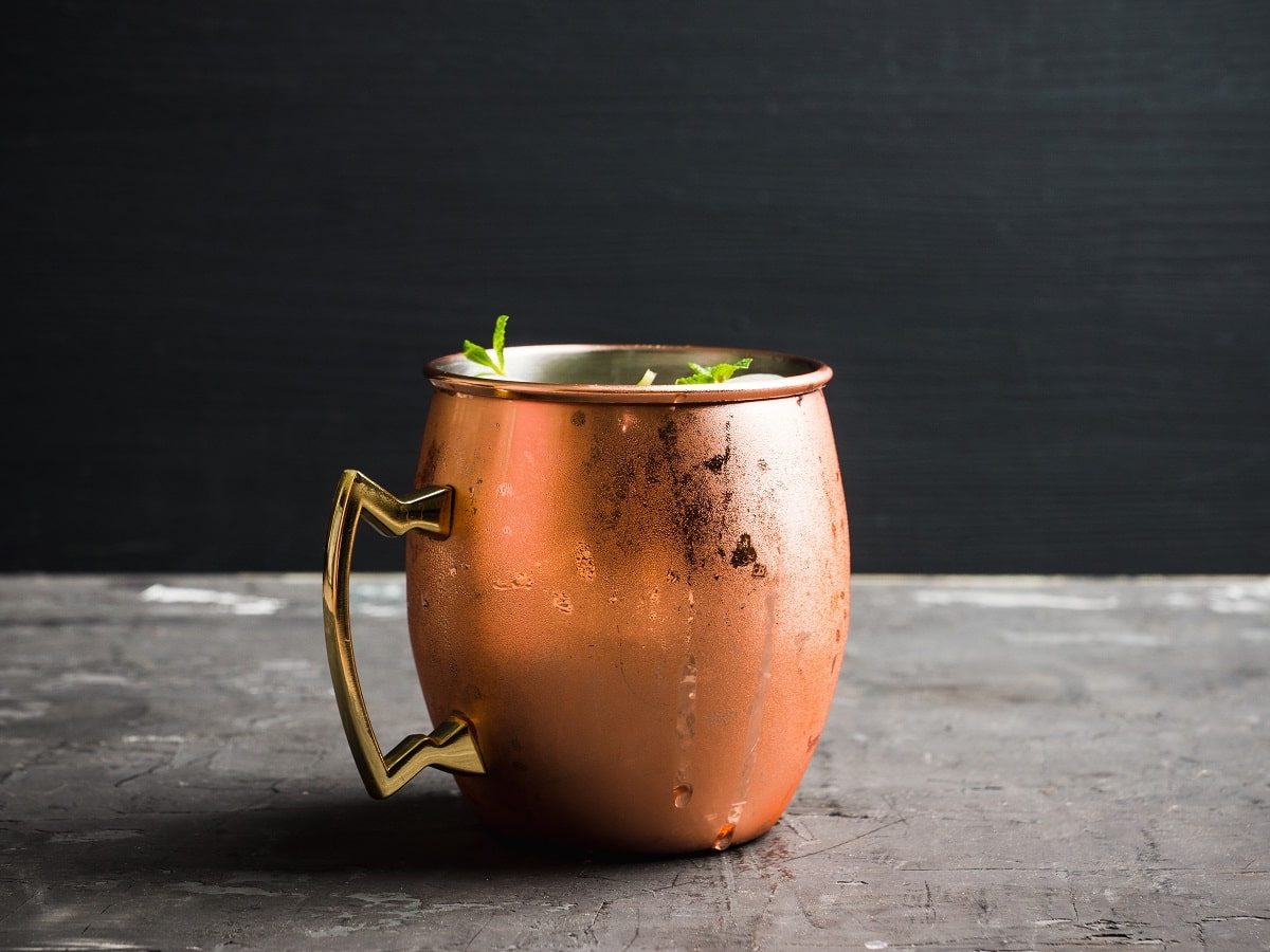 Eine kupferne Tasse mit Rhabarber Moscow Mule auf einem grauen Tisch.