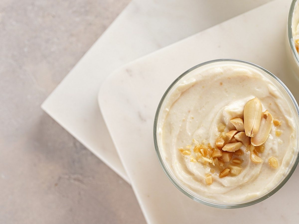 Zwei Dessertgläser mit Ricotta-Creme mit Tonkabohne auf einer Tafel.