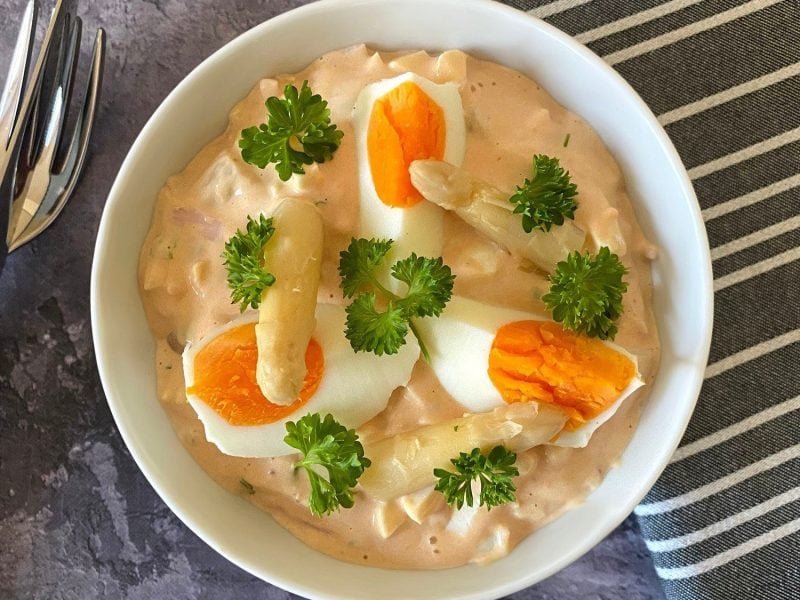 Eiersalat mit Schinken und Spargel in weißer Schüssel.