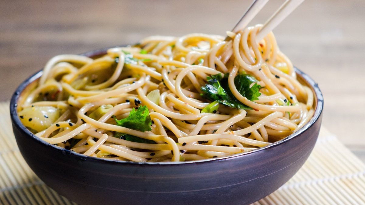 Eine Schüssel Cashew-Sesam-Pasta mit Kräutern, darin Essstäbchen.