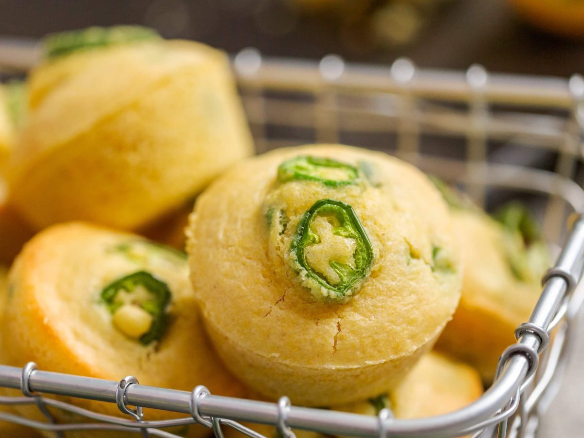 Ein Metallkorb mit den Chili-Cheese-Muffins auf einem hellen Tisch.