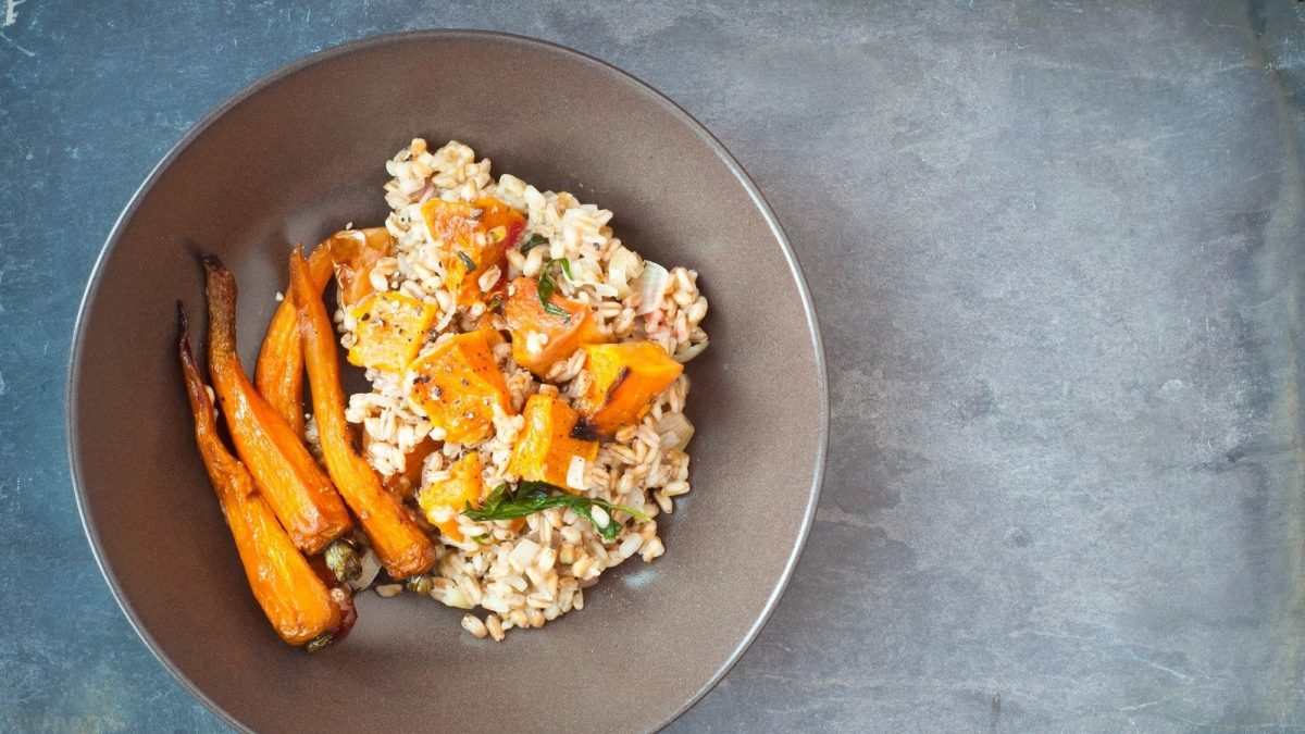 Eine Schüssel mit Dinkel-Risotto mit Ofengemüse auf einem grauen Tisch.