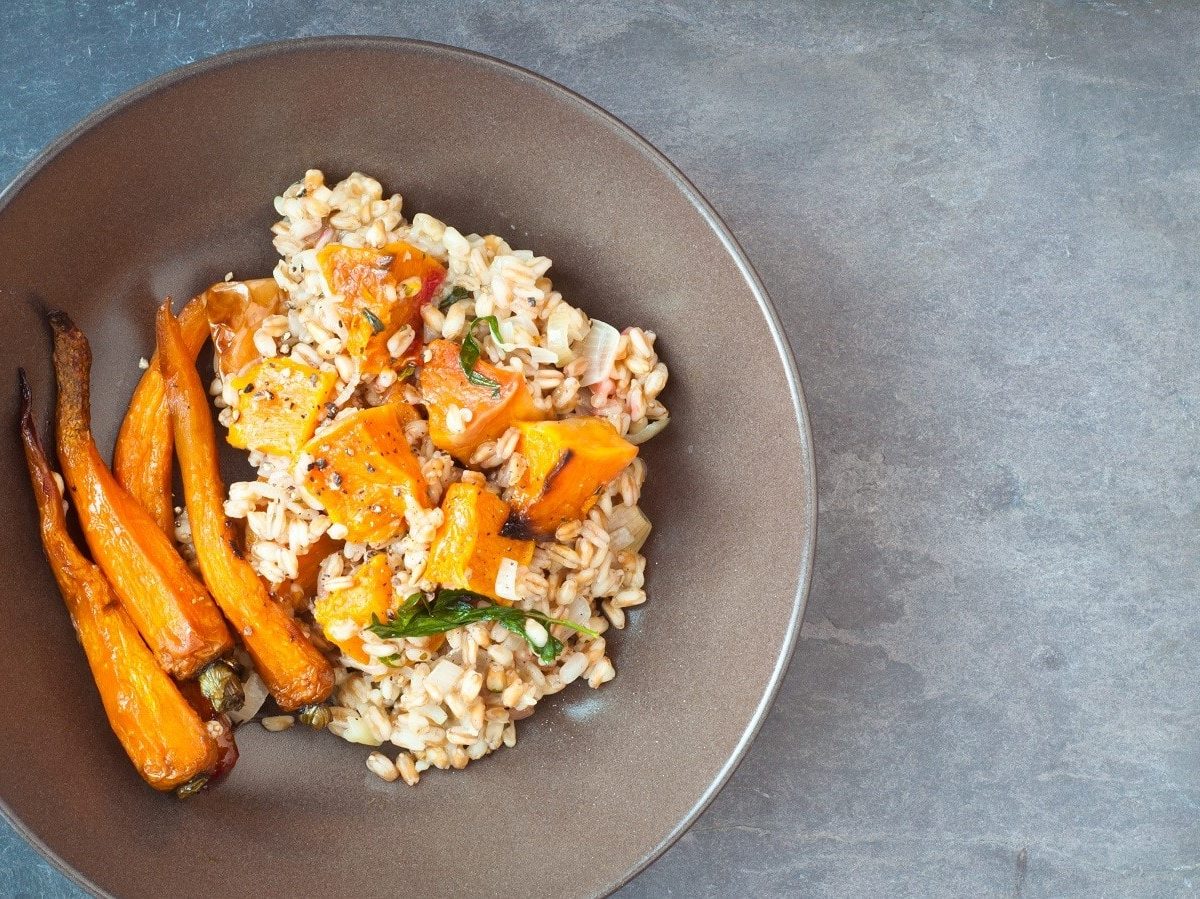 Eine Schüssel mit Dinkel-Risotto mit Ofengemüse auf einem grauen Tisch.