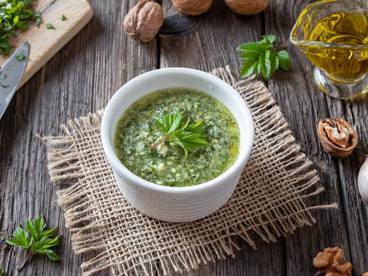 Eine kleine Schüssel mit Giersch-Pesto auf einem Stück Stoff.