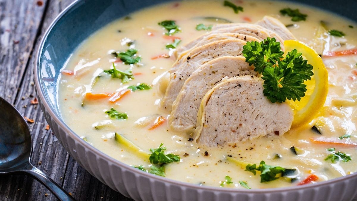 Eine tiefe Schale mit griechischer Zitronen-Cremesuppe auf einem dunklen Tisch.