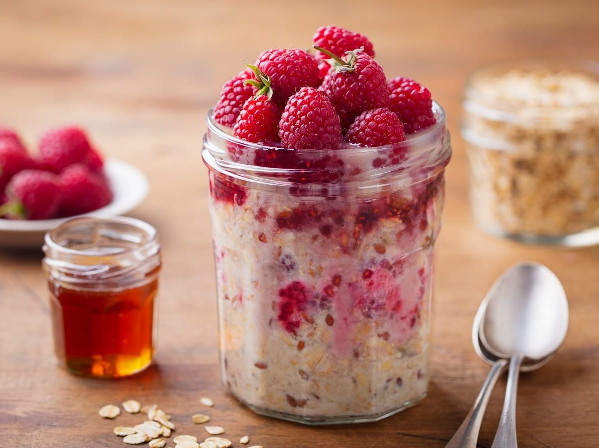 Ein Glas mit Kefir Overnight Oats mit Beeren auf einem Holztisch.