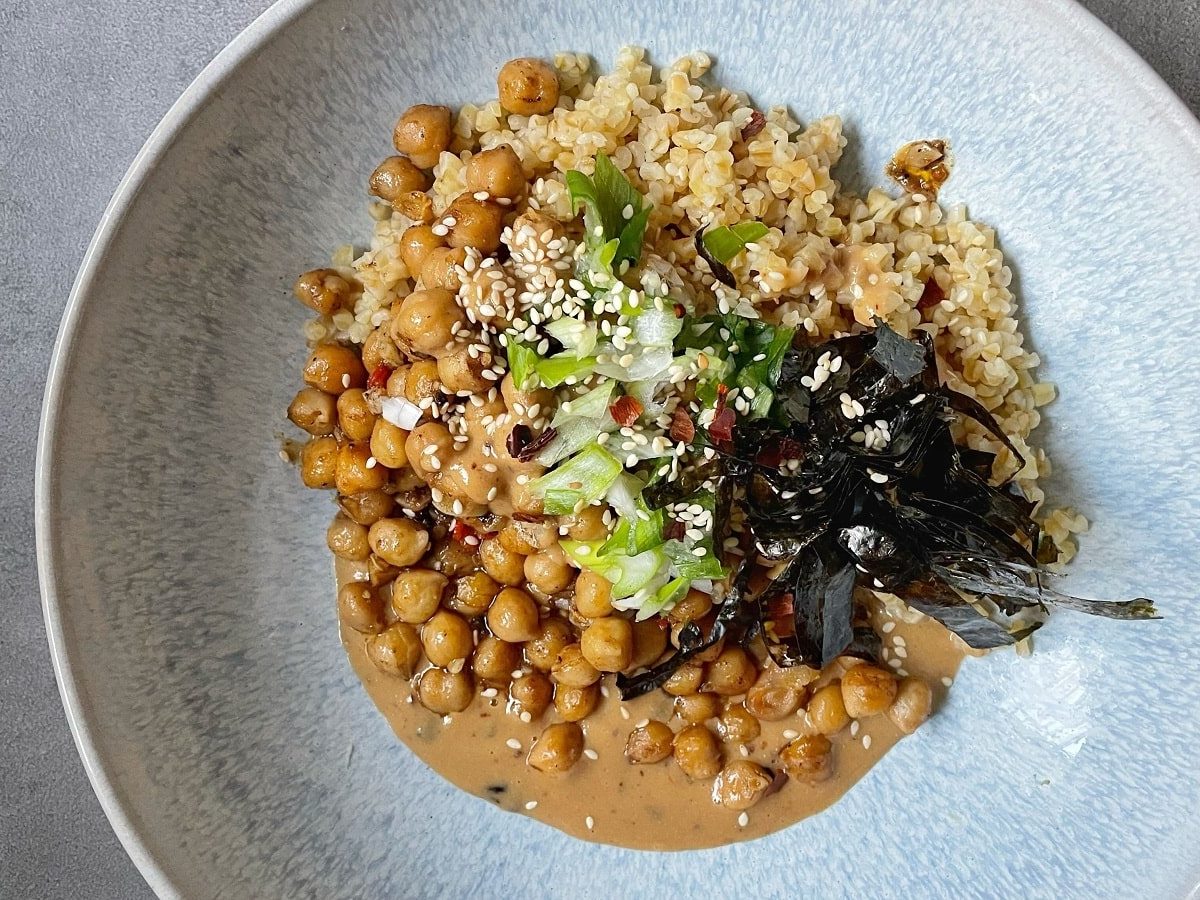 Eine Kichererbsen-Bowl mit Chili-Tahini auf einem grauen Tisch.