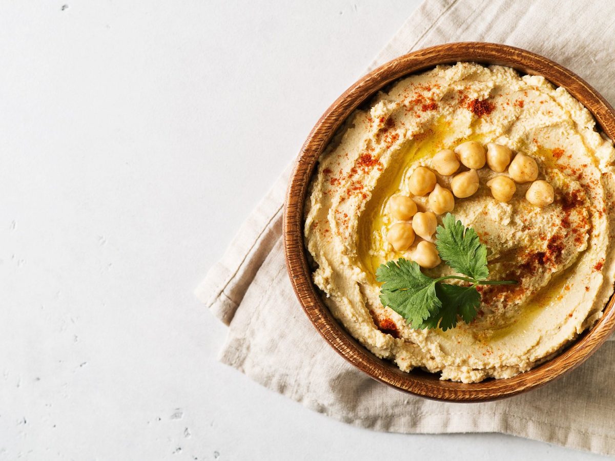 Eine Schale Hummus mit Kichererbsen, Gewürzen und Koriander dekoriert.