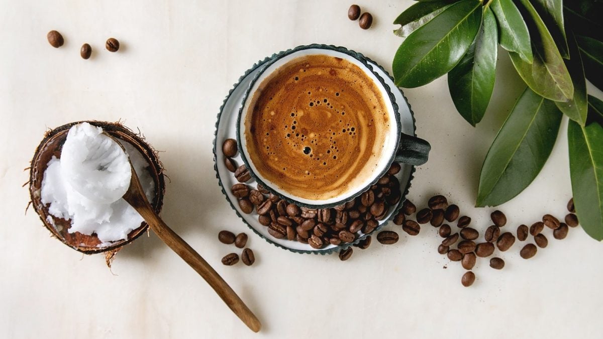 Eine Tasse Coco Coffee neben frischen Kaffeebohnen.