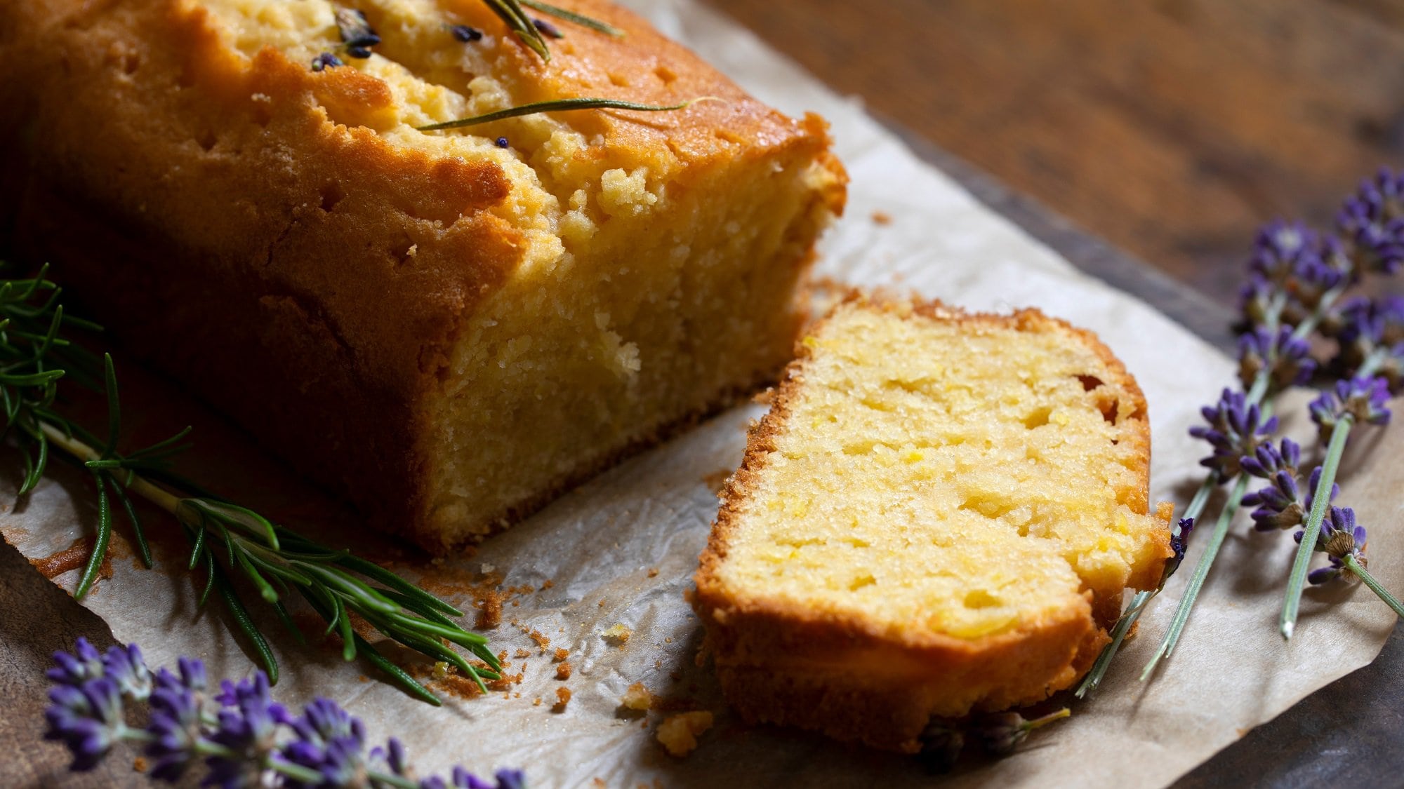 Ein angeschnittener Lavendelkuchen in Kastenform mit frischem Lavendel dekoriert.