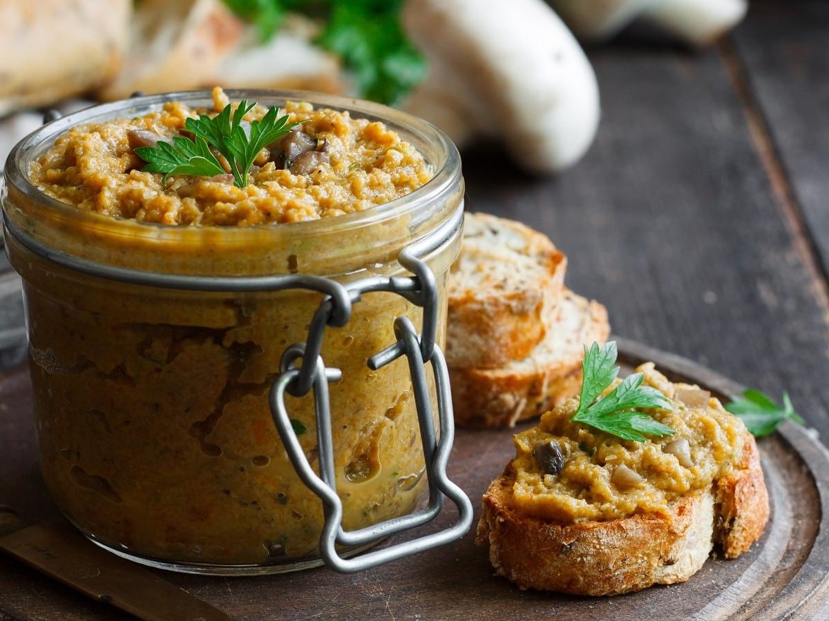 Ein Einmachglas mit Champignon-Linsen-Dip mit Holzbrett.